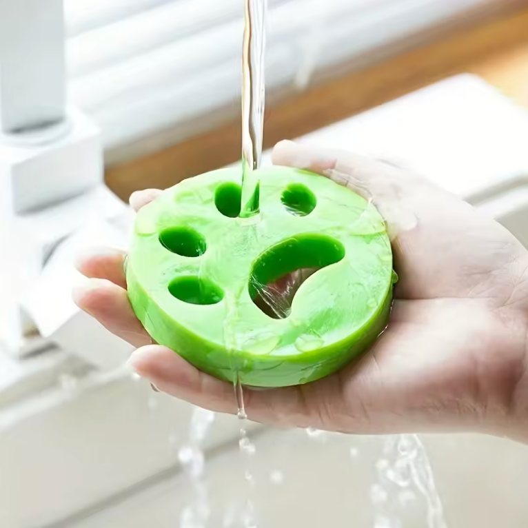 Green silicone hair remover with water being poured over it, held by a hand.